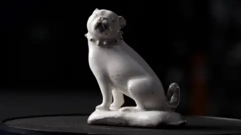 Tony Jolliffe BBC A complete figurine of a seated pug dog in plain white glazed porcelain with details picked out in black found at St James' Euston